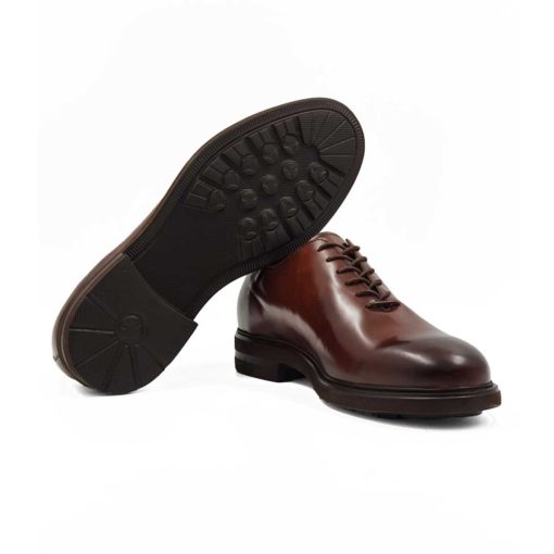 Muške elegantne braon cipele za odelo Cap Toe Oxford izradjene su od glatke teleće Nappa kože. Ručno su polirane da bi se dobila ujednačena blago zamagljena tamnobraon boja. Na ovom paru muške obuće je primenjeno vrhunsko znanje majstora koji su dokazali da za njih nema tajni u obućarskom zanatu. Da bi se naglasili šavovi i vrh cipele, još jednom su farbane tamnijom braon bojom. Diskretne bordure i štepovi dodatno ističu linearnu siluetu i snažan dizajn.