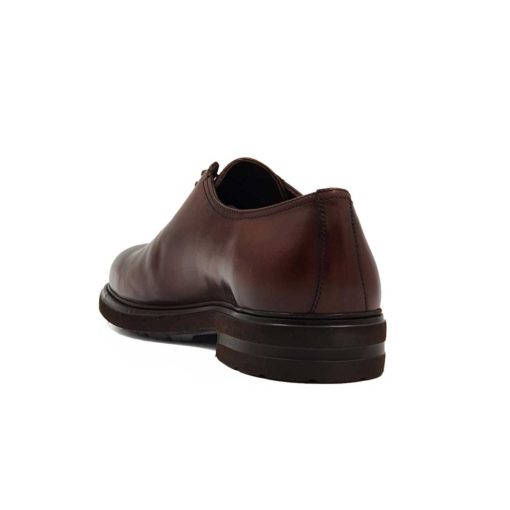 Muške elegantne braon cipele za odelo Cap Toe Oxford izradjene su od glatke teleće Nappa kože. Ručno su polirane da bi se dobila ujednačena blago zamagljena tamnobraon boja. Na ovom paru muške obuće je primenjeno vrhunsko znanje majstora koji su dokazali da za njih nema tajni u obućarskom zanatu. Da bi se naglasili šavovi i vrh cipele, još jednom su farbane tamnijom braon bojom. Diskretne bordure i štepovi dodatno ističu linearnu siluetu i snažan dizajn.